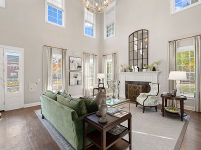 Upscale leasing office clubhouse clubroom featuring a high ceiling, white fireplace, green velvet sofa, and large windows at The Westbury apartments near Germantown.