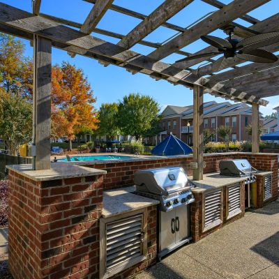 Outdoor resident grilling station featuring built-in stainless steel gas grills under a wooden pergola at The Westbury apartments near Germantown.