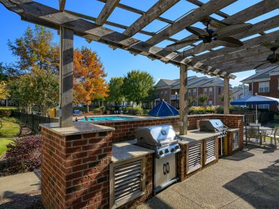 Outdoor resident grilling station featuring built-in stainless steel gas grills under a wooden pergola at The Westbury apartments near Germantown.