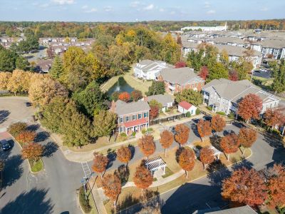 Aerial view of the leasing office building, manicured landscape paths, and a scenic retention pond at The Westbury apartments near Germantown.
