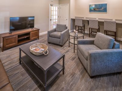 Community resident business center and media lounge featuring a television, plush chairs, and a laptop counter station at The Westbury apartments near Germantown.