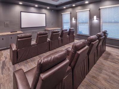 Private community movie theater room featuring tiered rows of brown leather recliners and a large projection screen at The Westbury apartments near Germantown.