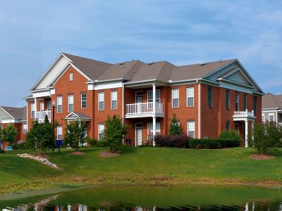 Front exterior view of upscale red brick apartment buildings featuring white columns and private balconies at The Westbury apartments near Germantown.
